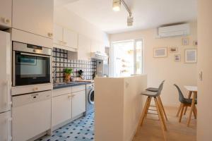Il comprend une cuisine avec des placards blancs, une télévision et une table. dans l'établissement Ile de Porquerolles, KerMarc, appartement lumineux avec grande terrasse, à Porquerolles