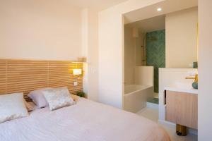 - une chambre avec un lit, un lavabo et une baignoire dans l'établissement Ile de Porquerolles, KerMarc, appartement lumineux avec grande terrasse, à Porquerolles