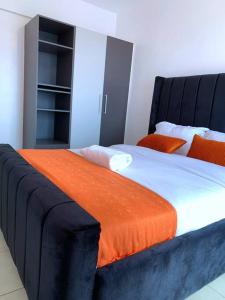 a bedroom with a large bed with an orange blanket at Modern 1-Bedroom Unit 5 mins from CBD in Nairobi