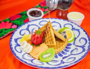 un plato azul y blanco con gofres, fruta y jarabe en Hotel Brisas 5a AV, Playa del Carmen en Playa del Carmen