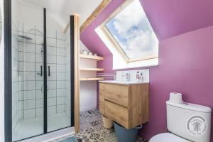 baño con paredes de color púrpura, aseo y ventana en Le jardin des fées, en Savigny-le-Vieux