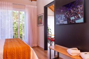 a bedroom with a large tv on the wall at Timber Lodge Camanducaia in Monte Verde