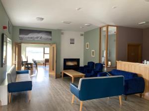 a waiting room with blue chairs and a fireplace at Achill Surf Centre in Mayo