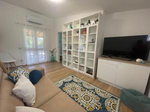 een woonkamer met een bank en een flatscreen-tv bij Villetta Palmina in Porto Azzurro