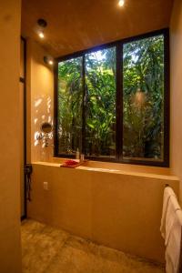 a bathroom with a large window and a bath tub at Hotel Maya Bell in Palenque