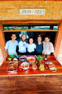 a group of people standing around a table with food at Pousada Ninho da Gralha in Turvo