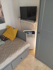 - une petite chambre avec un lit et une télévision dans l'établissement Paris-Eiffel, bienvenue -terrasse -Netflix, à Pantin