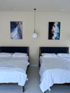 two beds in a bedroom with two paintings on the wall at Eleven8 Taman Pandan in Alor Setar