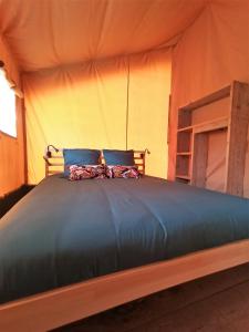 a bed in a tent with two pillows on it at Le Lodge du Hibou in Quarré-les-Tombes