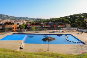 ein großer Pool mit Sonnenschirm und Stadt in der Unterkunft Apartments Sa Boadella, Lloret de Mar - Costa Brava in Lloret de Mar