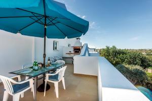 a patio with a table and an umbrella at Casa Alto do Perogil Tavira-3 bedroom house with pool & free wifi in Tavira