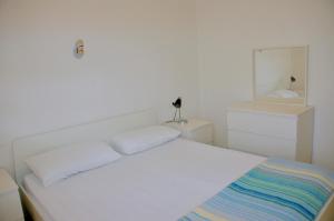a white bedroom with a bed and a mirror at Condominio Al Mare in Bibione