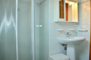 a white bathroom with a sink and a shower at Condominio Al Mare in Bibione +2 photos