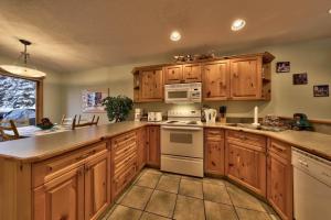 a kitchen with wooden cabinets and a white stove top oven at Snow Creek Village #20 By Bear Country in Sun Peaks