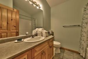 ein Badezimmer mit einem Waschbecken, einem WC und einem Spiegel in der Unterkunft Snow Creek Village #20 By Bear Country in Sun Peaks