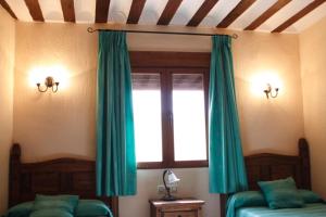 1 dormitorio con 2 camas y una ventana con cortinas verdes en Casa Rural El Acebo, en Almodóvar del Pinar
