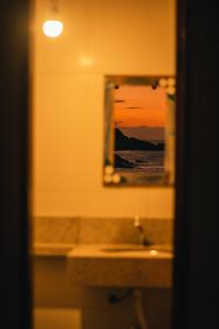 La salle de bains est pourvue d'un lavabo et d'un miroir. dans l'établissement Chalé na Praia de Ponta Negra, à Ponta Negra