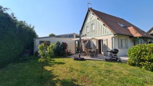 a white house with a patio and a yard at Villa 5*, mer à 3 mn, piscine intérieure à 28° in Gonneville-en-Auge