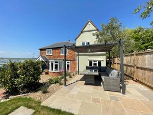 a patio with a couch under a pergola at Cosy Coastal 2-Bedroom Cottage with Hot Tub and Log Burner in West Mersea