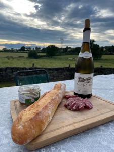 a bottle of wine and a loaf of bread on a table at Les Ecureuils, chambre au calme in Bussy-la-Pesle