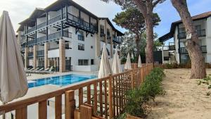 een resort met een zwembad en parasols bij Hôtel Ibaia in Hendaye