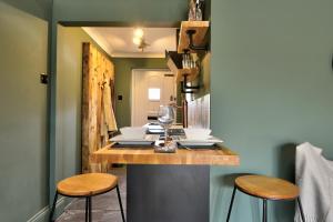 eine Küche mit einer Theke mit Hockern und einem Tisch mit Weingläsern in der Unterkunft Annex by the Sea in Lancing