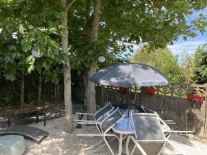 einen Tisch und Stühle unter einem Regenschirm im Hof in der Unterkunft Le Gai Lo Gite in Villers-Pol