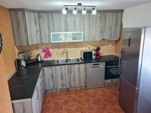 eine Küche mit Holzschränken und einem Kühlschrank aus Edelstahl in der Unterkunft Vila Tea Fruska Gora in Čortanovci