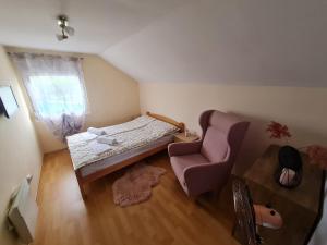 ein kleines Schlafzimmer mit einem Bett und einem Stuhl in der Unterkunft Vila Tea Fruska Gora in Čortanovci
