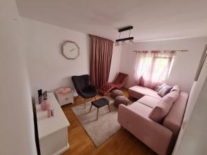 ein Wohnzimmer mit einem rosa Sofa und einem Stuhl in der Unterkunft Vila Tea Fruska Gora in Čortanovci