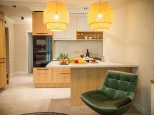 kuchnia z zielonym krzesłem i lampkami w obiekcie Panorama Deluxe Apartments - pool, sauna, fitness w Alsóörs