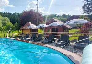 a pool with chairs and umbrellas and a house at GREEN LAND Family Fun Sport Resort in Šmarje pri Jelšah