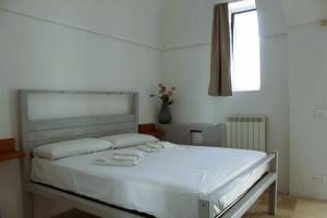 Cama blanca en habitación con ventana en Masseria Piccole Taverne en Rosa Marina