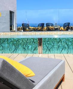 Design Plus Bex Hotel في لاس بالماس دي غران كاناريا: مسبح وكراسي وسرير امام الماء