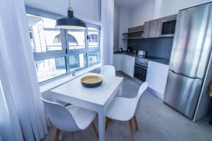 cocina con mesa blanca, sillas y nevera en Bex Holiday Homes, en Las Palmas de Gran Canaria