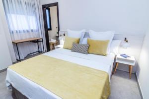 Un dormitorio con una gran cama blanca con almohadas amarillas. en Bex Holiday Homes, en Las Palmas de Gran Canaria