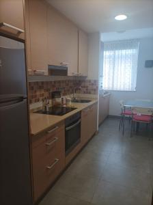 a kitchen with a sink and a refrigerator and a table at Apartamento A Rapadoira Foz in Foz