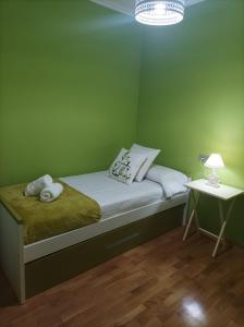 ein grünes Schlafzimmer mit einem Bett und einem Nachttisch in der Unterkunft Apartamento A Rapadoira Foz in Foz