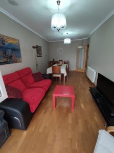 ein Wohnzimmer mit einem roten Sofa und einem Tisch in der Unterkunft Apartamento A Rapadoira Foz in Foz