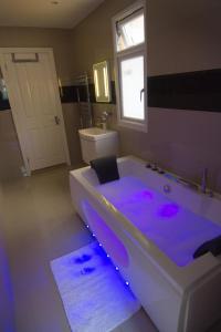 a bathroom with a tub with purple lights in it at Abbey Canterbury in Kent