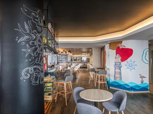 um restaurante com mesas e cadeiras e uma parede com um mural em Ibis Styles Lisboa Centro Liberdade NE em Lisboa