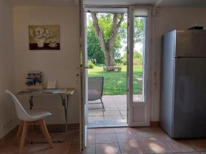 een keuken met een koelkast, een tafel en een bureau bij Le Gîte Les Grives in Villers-Carbonnel