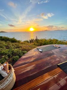 a wooden deck with a sunset over the ocean at The Aerial, BVI All-Inclusive Private Island in Tortola Island