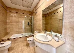 a bathroom with a sink and a toilet and a tub at Reinapart Patacona Beachfront Seaview in Valencia
