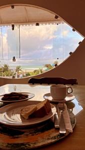 uma mesa com um prato de comida numa mesa com uma janela em Pousada Acácias dos Corais em Cabo de Santo Agostinho