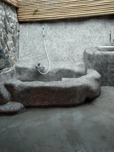 eine Steinbadewanne neben einer Wand mit einem Waschbecken in der Unterkunft 愛上龍過脈民宿 in Ch'u-lu