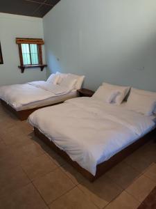 two beds in a room with white sheets at 愛上龍過脈民宿 in Ch'u-lu