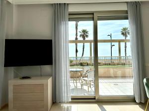 a living room with a television and a balcony with palm trees at Reinapart Patacona Beachfront Seaview in Valencia