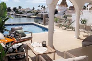 a patio with a pool and chairs and a table at Casa Serenity au canal avec piscine et amarre in Empuriabrava