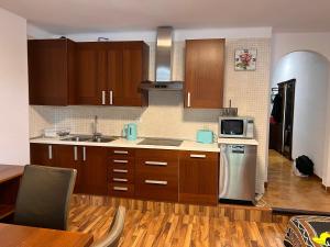 eine Küche mit Holzschränken, einer Spüle und einer Mikrowelle in der Unterkunft Apartamento las Palmeras in Roses